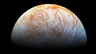 Měsíc Europa protkaný pavučinou prasklin v ledové krustě. Složený snímek pořídila sonda Galileo.