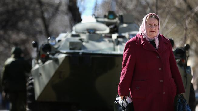 Stará žena v Simferopolu, za ní ruský tank