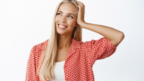 feminine-young-blond-woman-holding-hand-head-gazing-aside-with-dreamy-smiling-face-expression-standing-summer-outfit-white-background