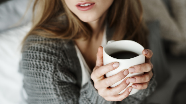 unrecognizable-woman-with-coffee-mug-bed