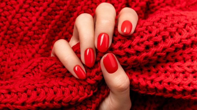 woman-s-hand-sweater-with-red-manicure-gray