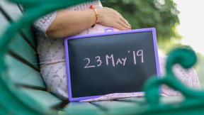 midsection-pregnant-woman-with-date-writing-slate
