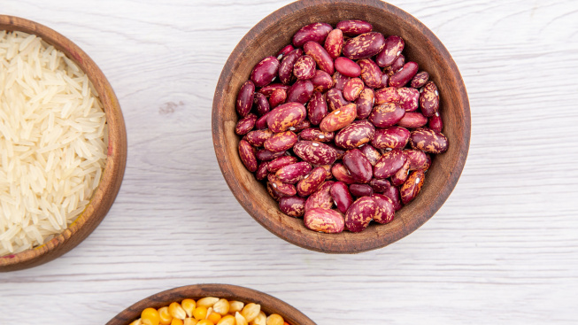 half-shot-fresh-beans-rice-corn-kernels-yellow-lentils-brown-bowls-white-table-view