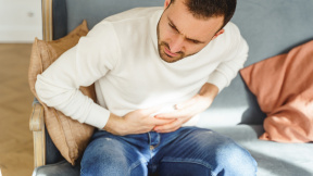 top-view-cheerless-male-suffering-from-severe-abdominal-pain-sofa