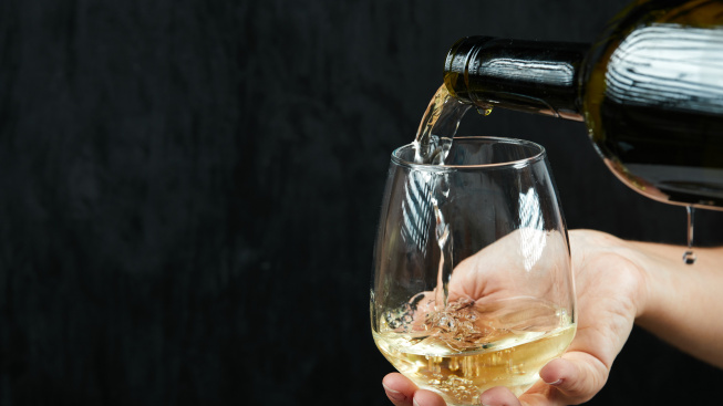 pouring-white-wine-into-wine-glass-dark-surface